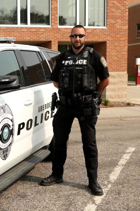 Officer Paul stands next to a patrol car