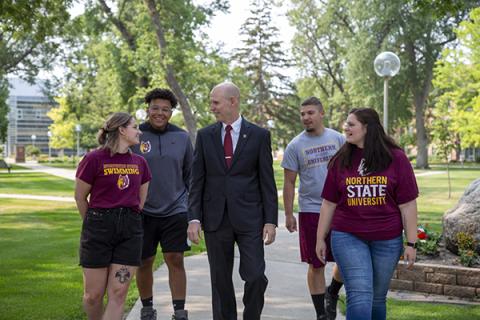 President Neal Schnoor walks across the campus green with students in Northern clothing