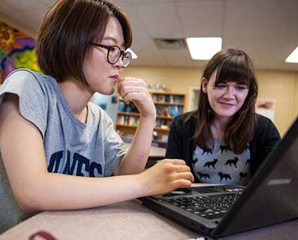 Two students look at a laptop