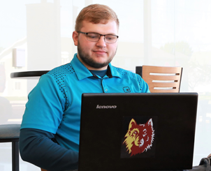 Male student on laptop with NSU logo