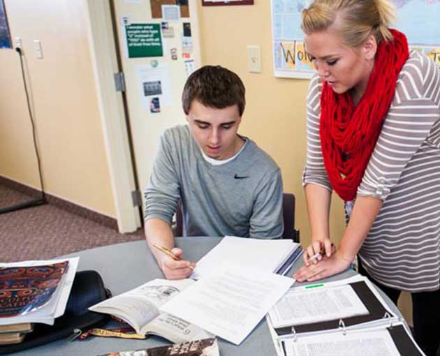Student teacher helping young male with school work