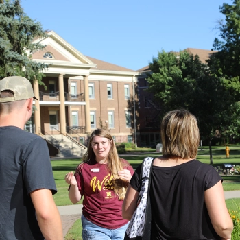 Tour participants listen to a guide on campus