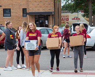 Student helpers carry items on move-in day