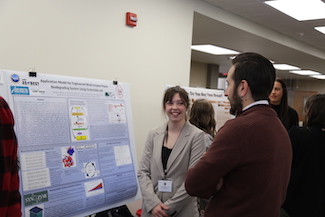 Female student discussing research poster with judge