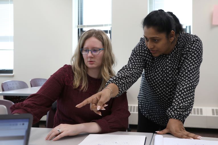 A student and instructor look at a laptop