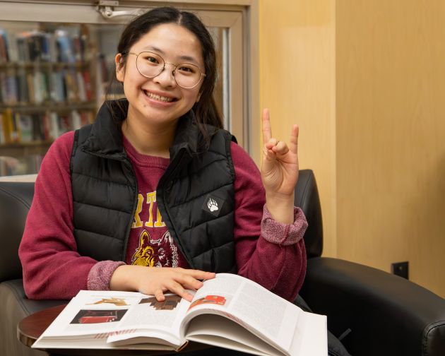 a smiling student with a textbook