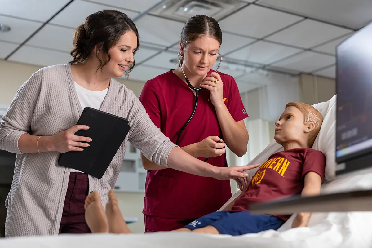 Nurse using a stethoscope on a manikin