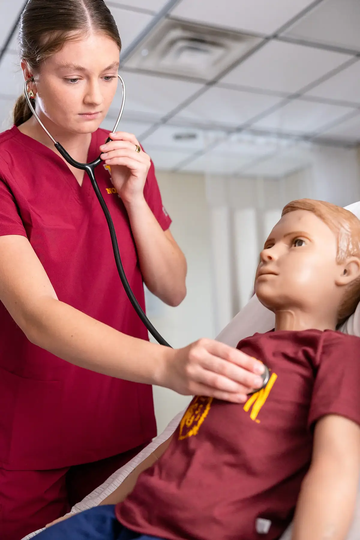 Nurse using a stethoscope on a manikin