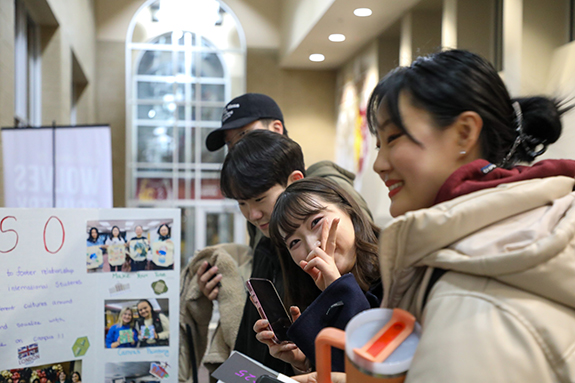 Exchange student takes a photo at a research fair booth