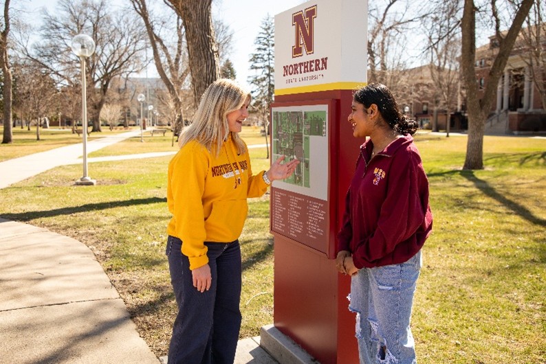 two students chatting outside by the university map