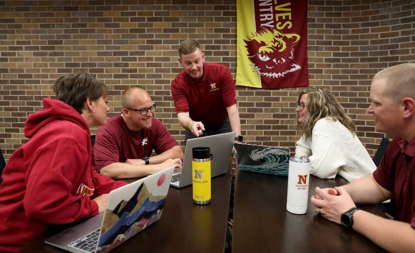 a professor explains material on a laptop to graduate students