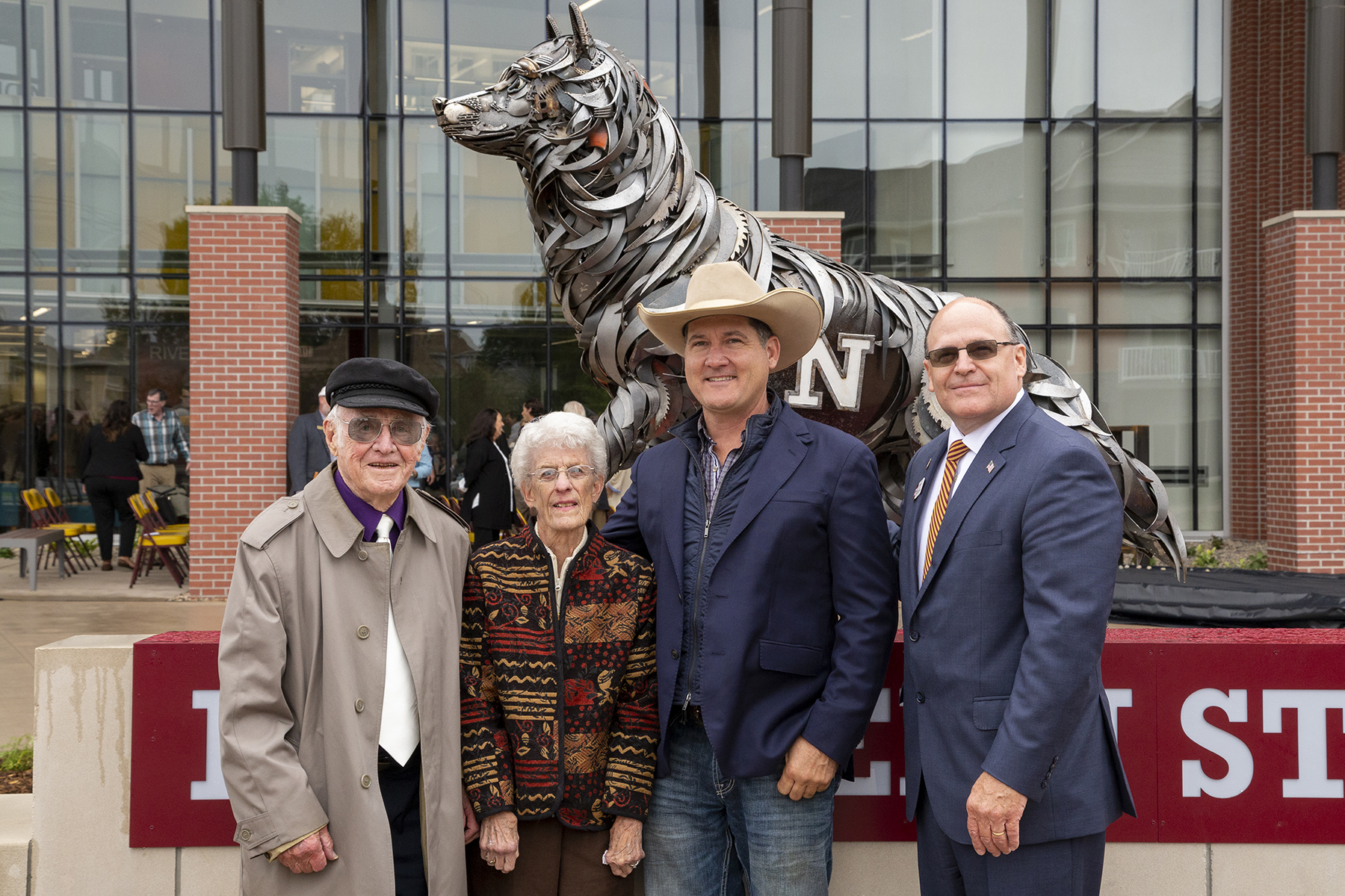 Ka and Sally Squire and sculptor John Lopez posing together in front of the NSU Wolf statue