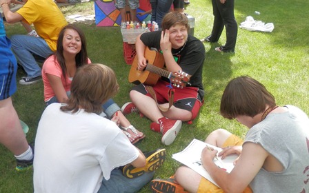 Seated students interact on campus green