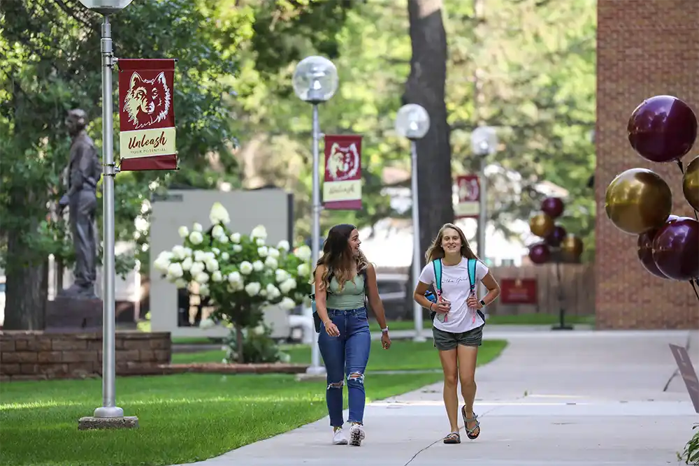 Two students walking on a sidewalk on the NSU campus