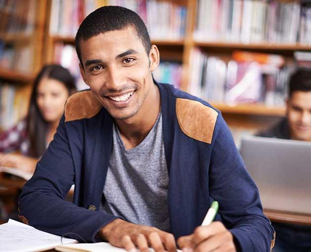 Male student smiling and writing