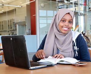 Student smiling in front of laptop and notes
