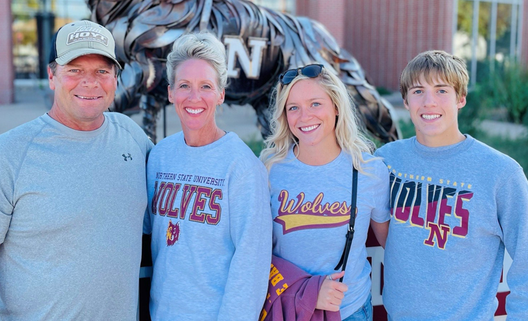 Family of four standing in front of NSU wolf statue