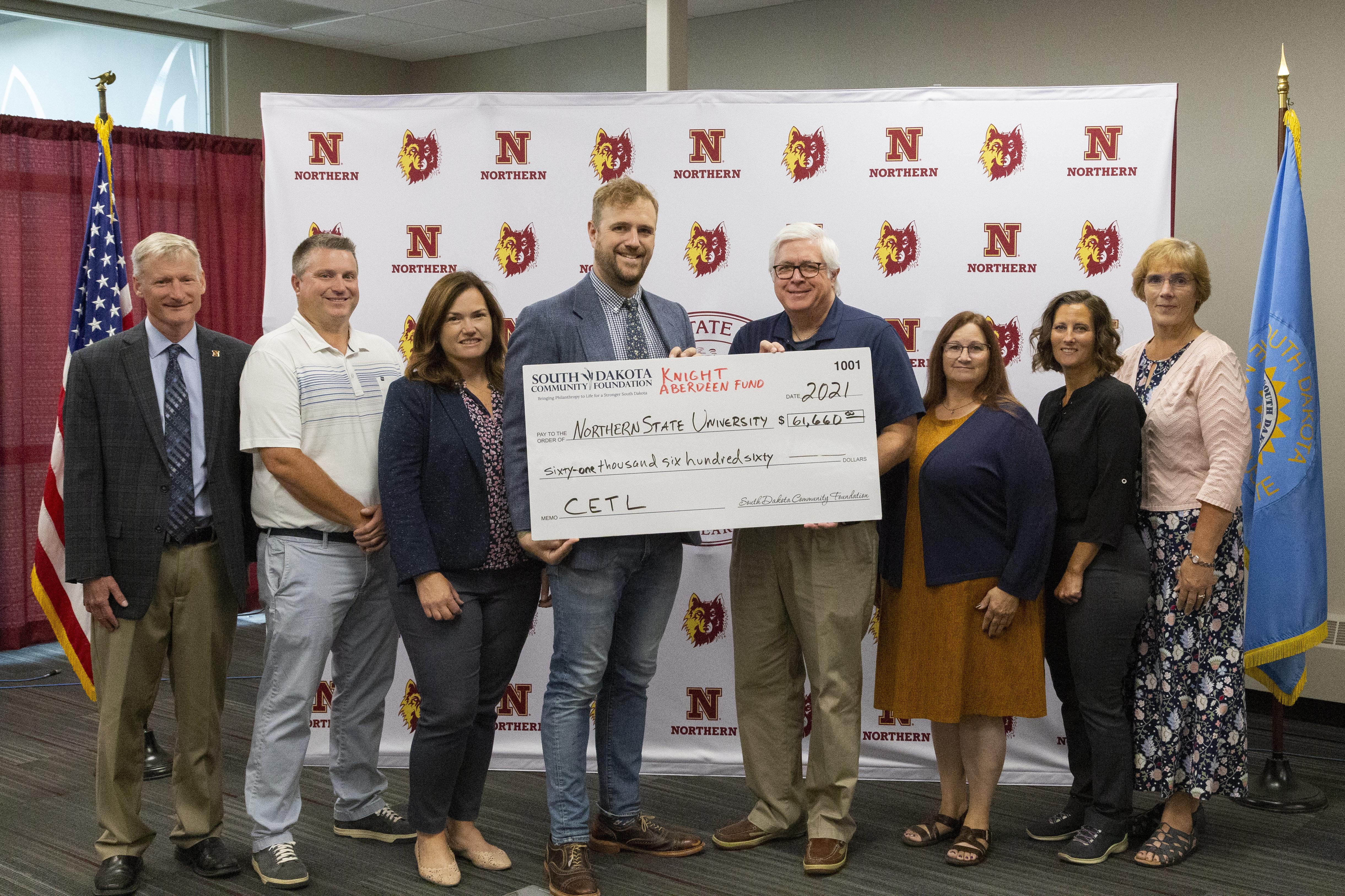 Group photo of men and women holding a large check