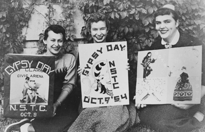 Black and white photo of 3 females holding signs