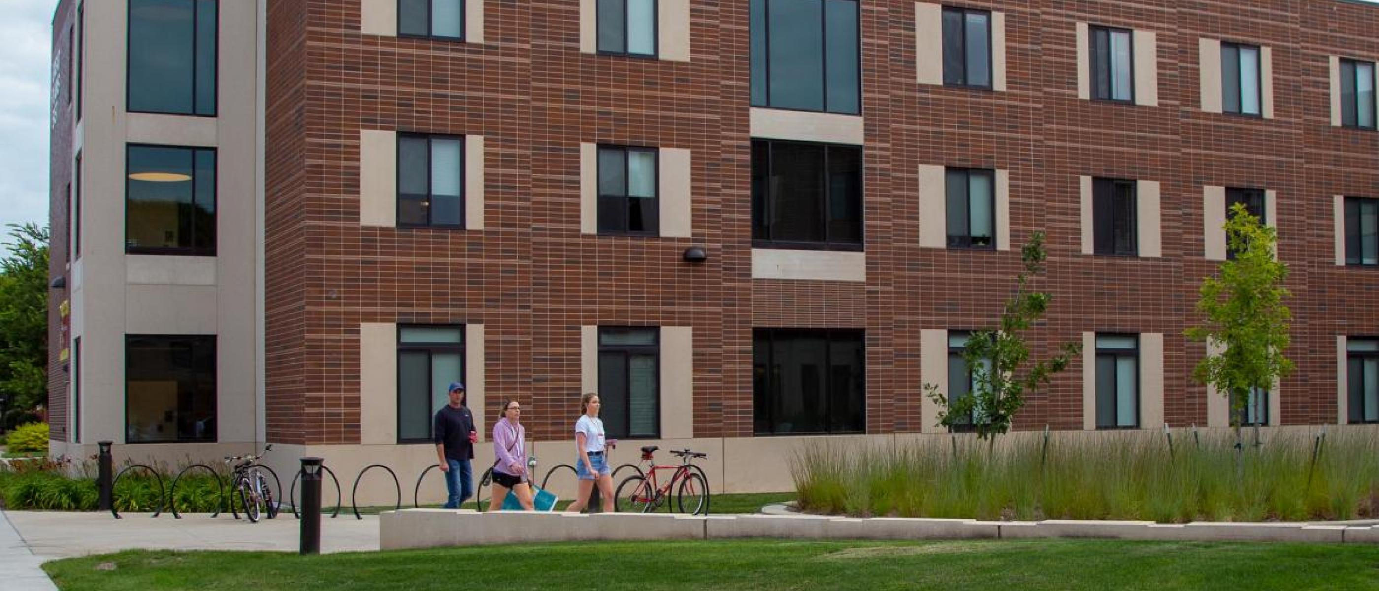 Three students walk in front of one of Northern's newest residence halls