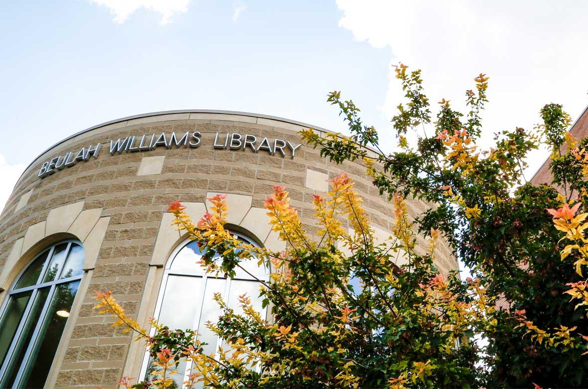 Top of the Beulah Williams Library Round Room exterior with fall-color tree branches visible