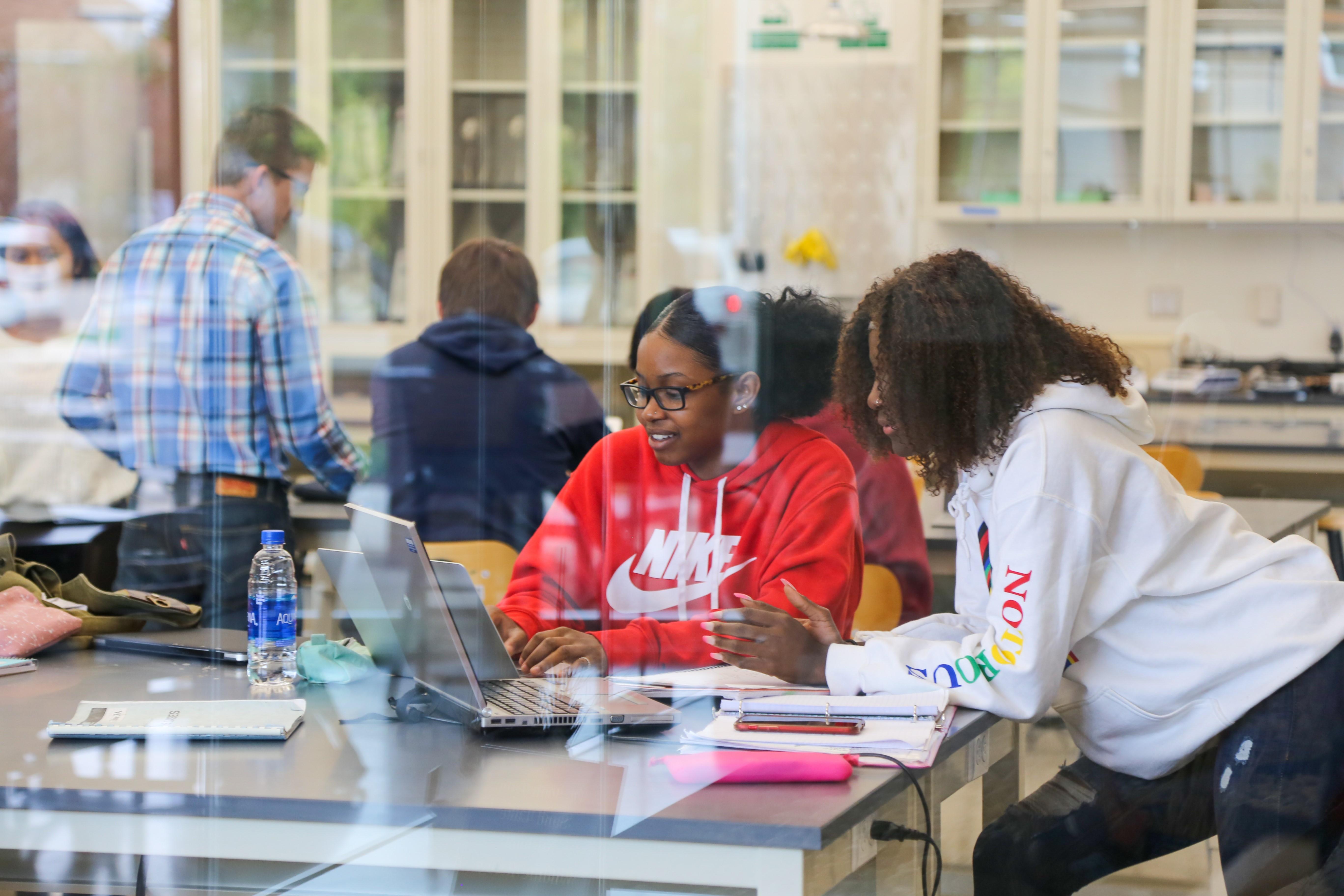 Two students looking at laptop on a science lab table