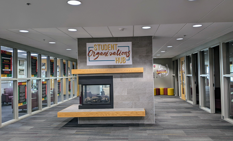 View of the Student Organizations Hub in the Avera Student Center with glass-fronted offices and fireplace