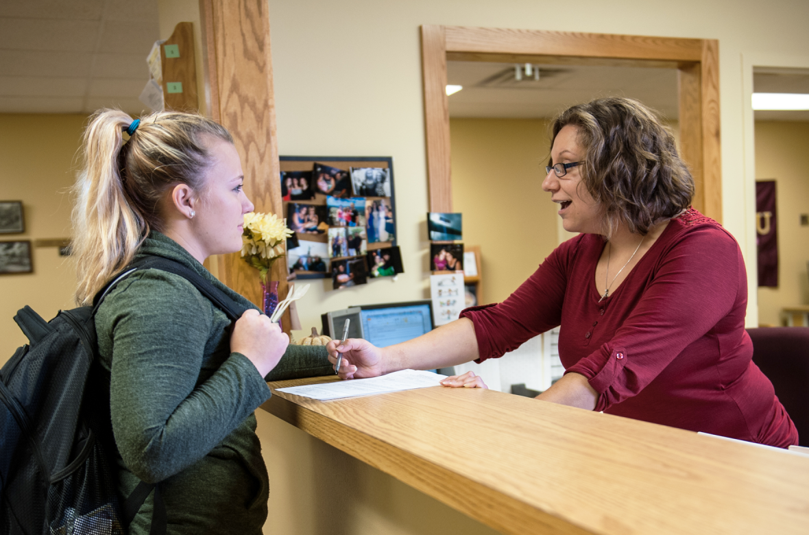 Employee helping student complete paperwork