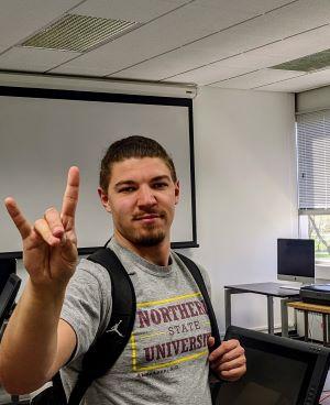 Dylan Duvall, in a gray Wolves T-shirt and backpack, waves