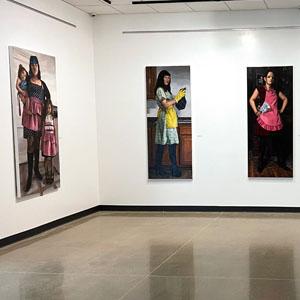 Large pictures with feminine themes hang on white gallery walls