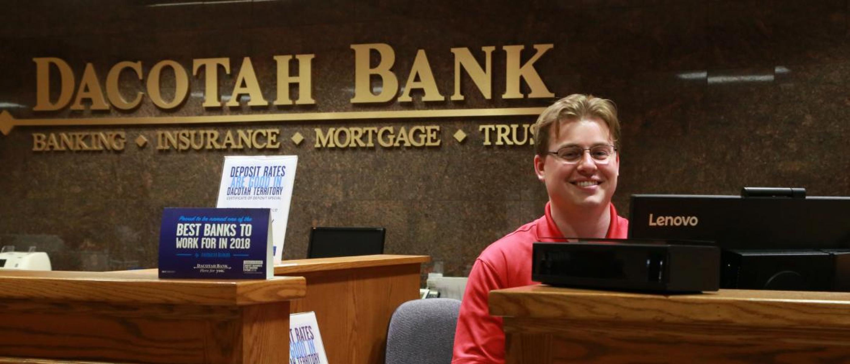 Bank teller smiling at desk in Dacotah Bank