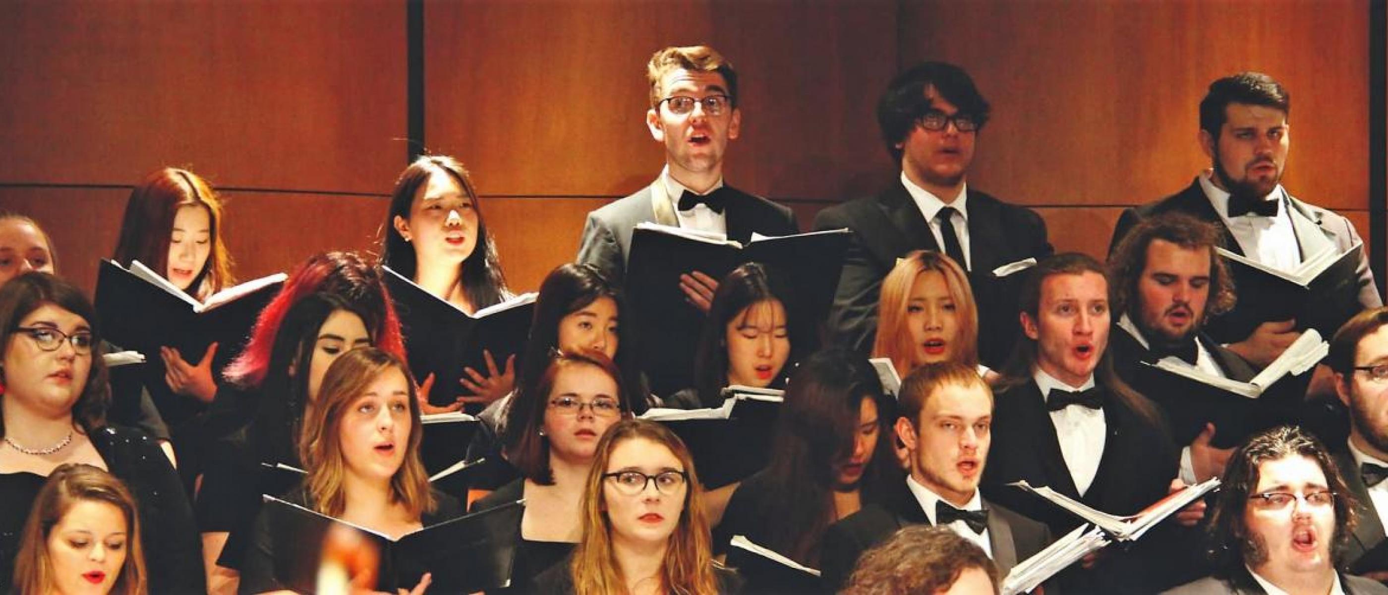 Students holding sheet music singing in choir