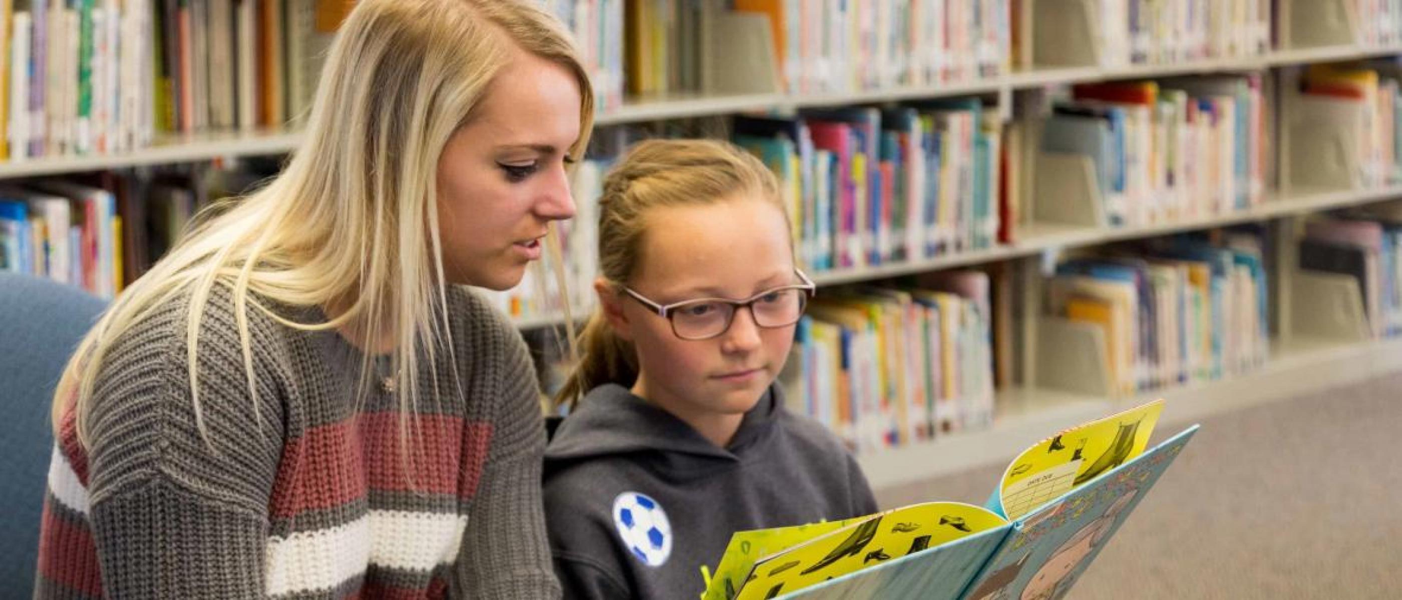 NSU student reading a children's book with child