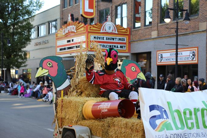 A parade float features a person in pheasant costume