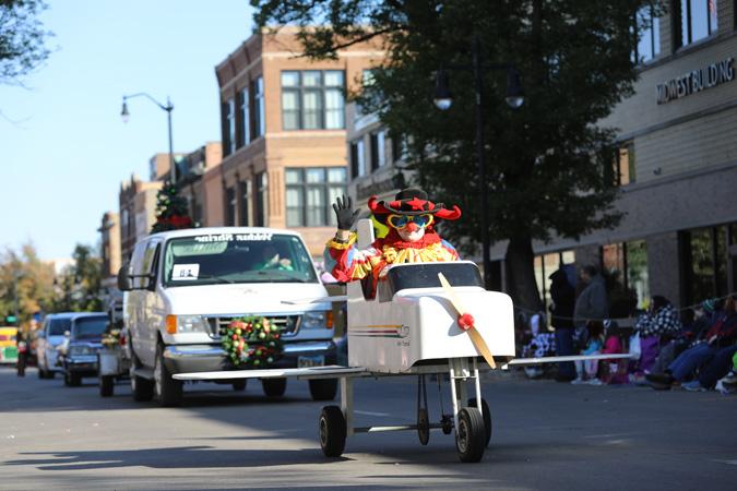 A parade float shows a clown in an airplane