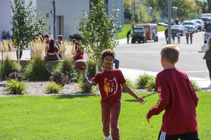 Kids lay football on the grass by Dacotah Bank Stadium