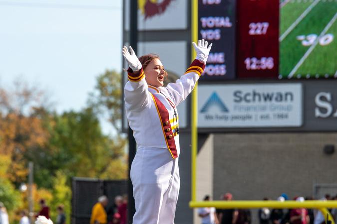  A marching band member in white raises their arms
