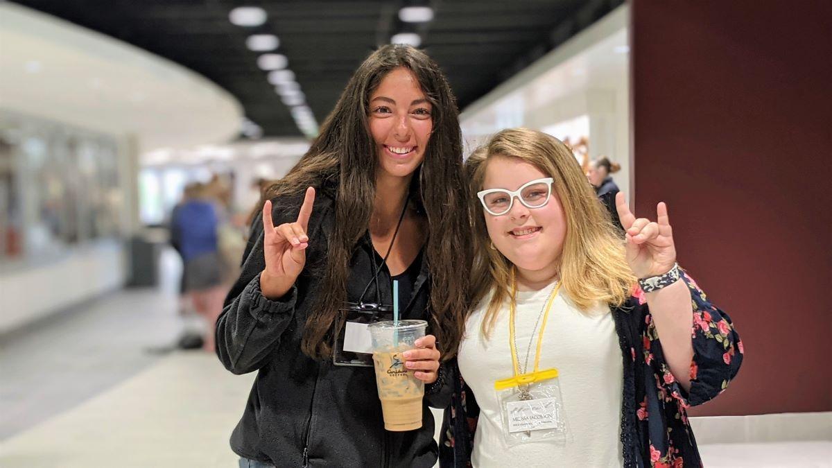 two students smile and gesture 