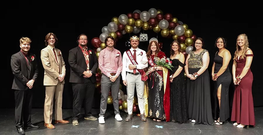 Homecoming royalty stand in a group on stage