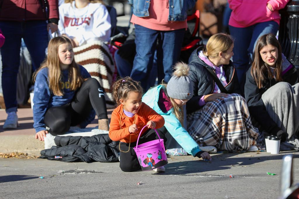 Children grab candy from the street during the parade