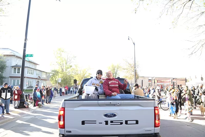 Parade-goers ride in the back of a pickup