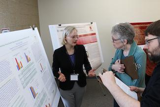 Student discussing her research poster with two judges