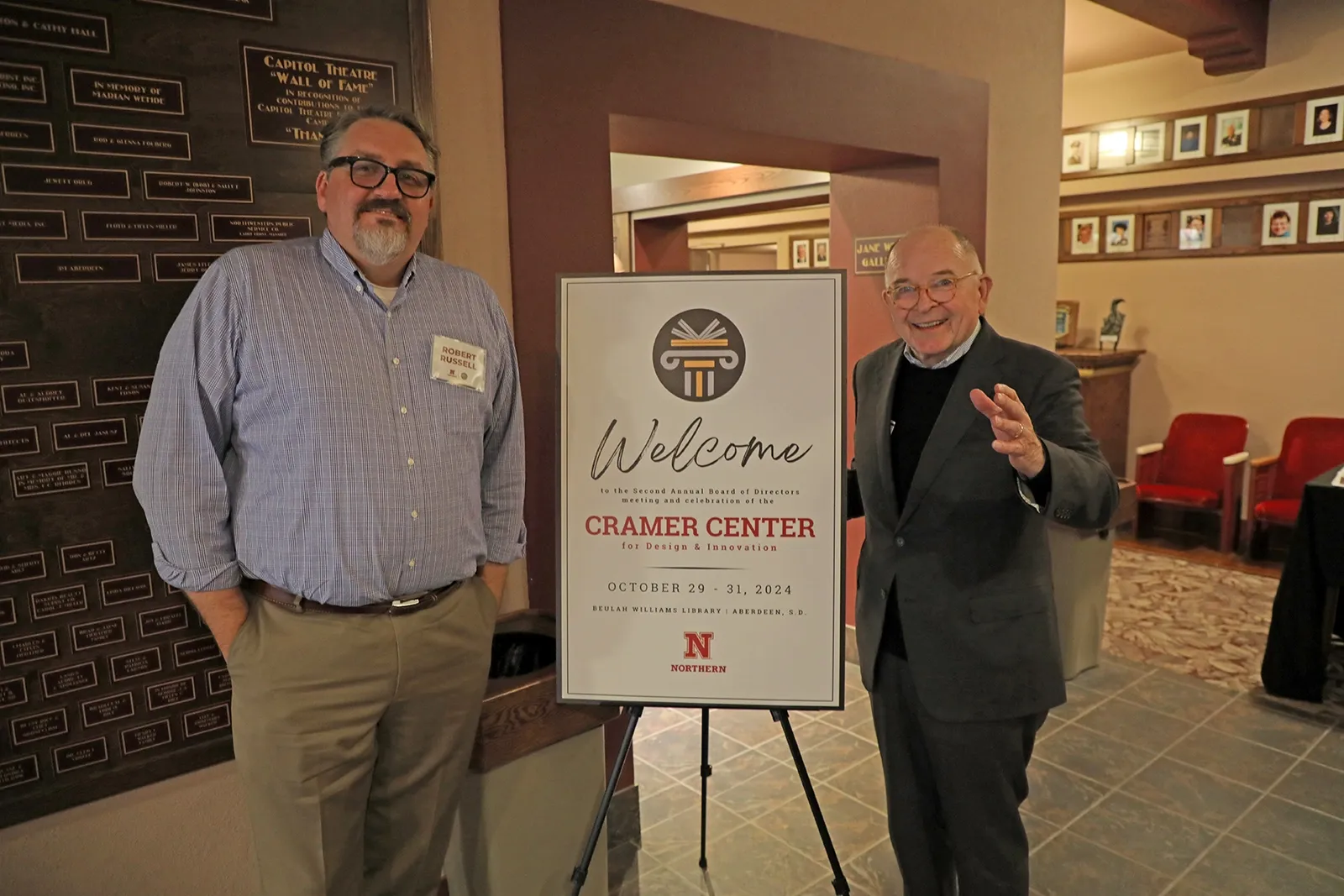 Two People standing next to a Welcome sign