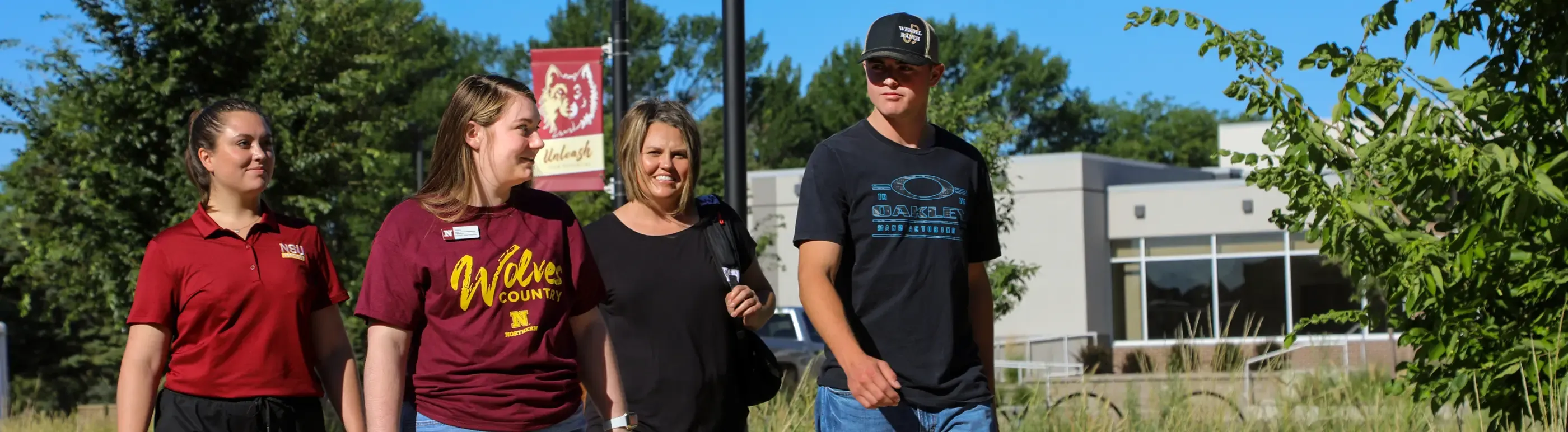 A mother and son walking on campus with NSU tour guides