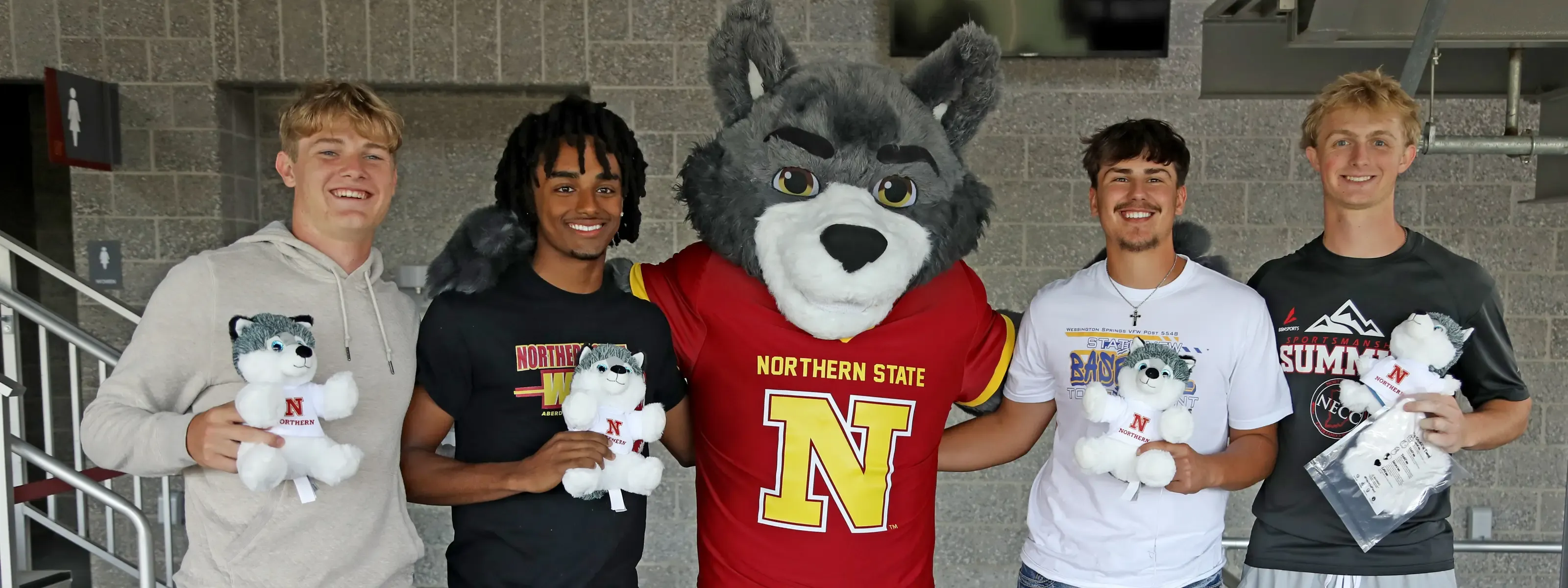 Four students posing with Thunder mascot with stuffed wolf animals