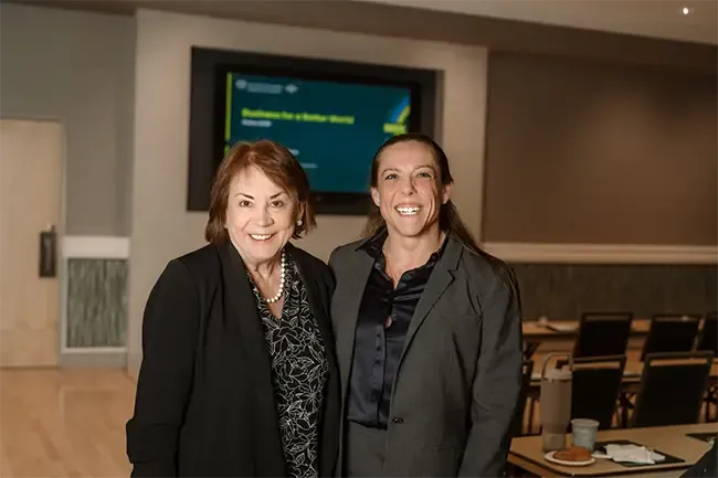 Dr. Amanda Garrison and another woman smiling at the camera in dark clothing