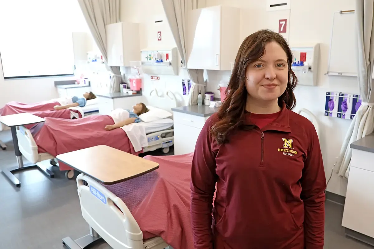 Sara Clough standing in front of a hospital bed in the simulation lab
