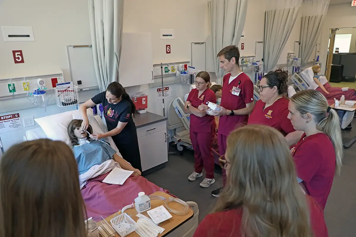 Nursing student standing around a hospital bed in a lab