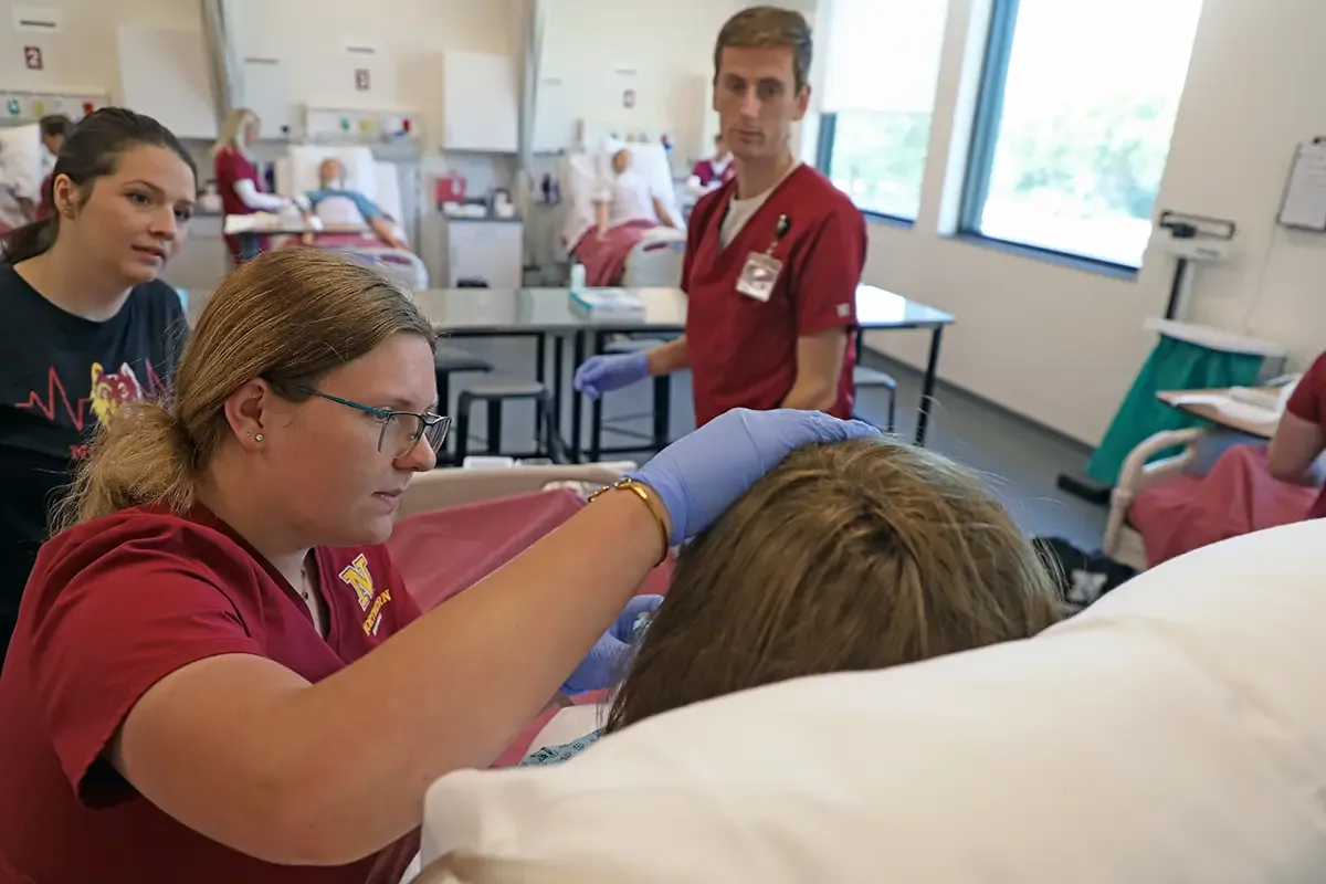 Nursing students working on a simulation dummy