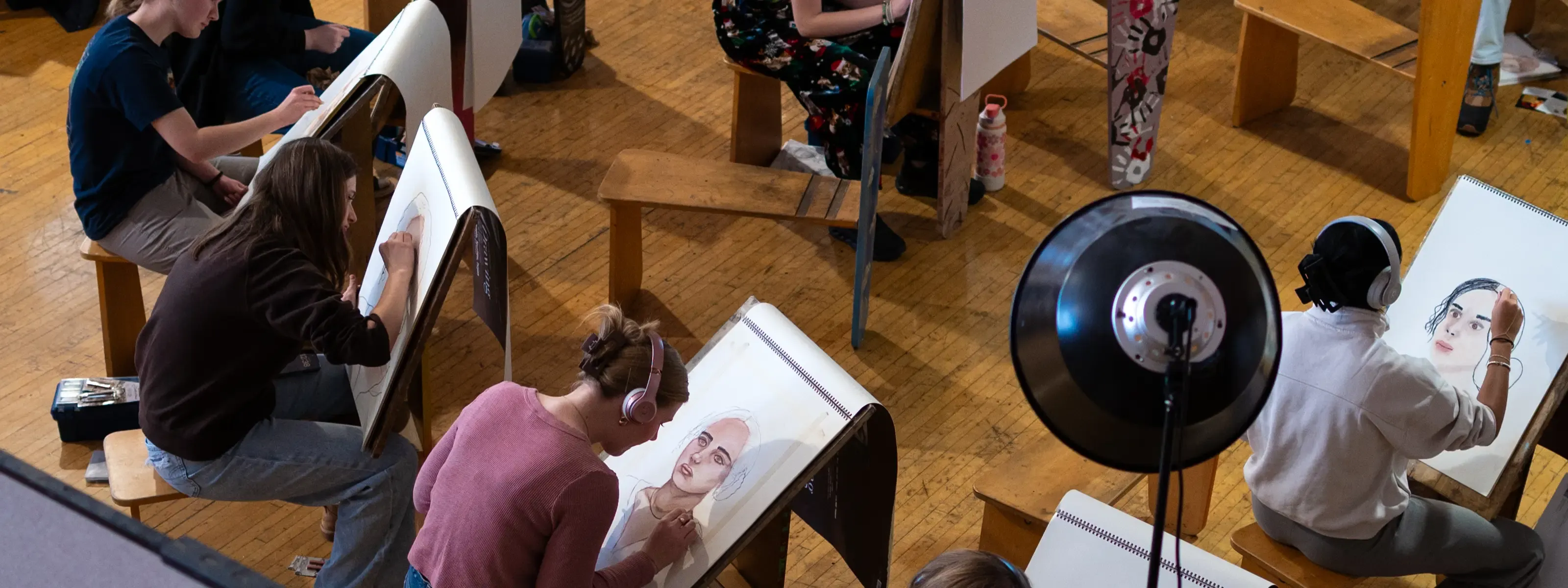 Students drawing a portrait of a person on individual easels. 